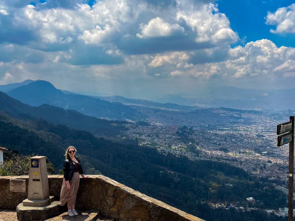 The author Taylor Herperger, smiling for a photo with an overlooking view of Bogota from the top of Monserrate