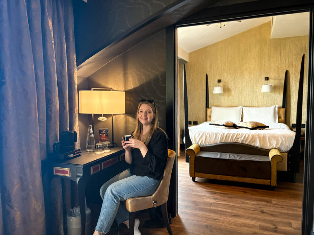 The author Taylor Herperger, sitting at the workstation with the bedroom view behind in Palazzo Veneziano