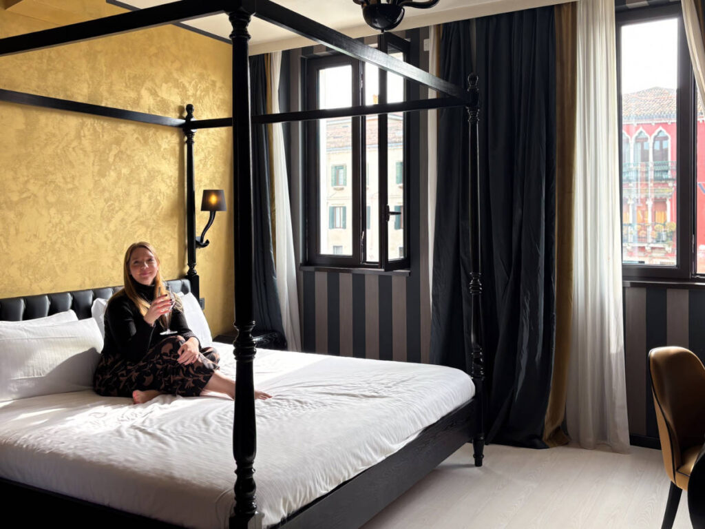 The author Taylor Herperger, sitting on her four-poster bed at Carnival Palace