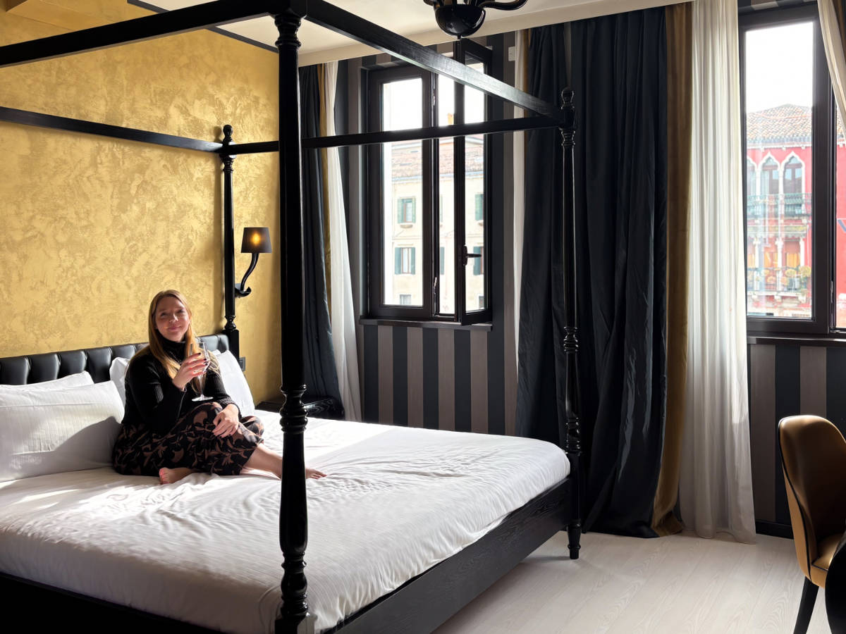 The author Taylor Herperger, sitting on her four-poster bed at Carnival Palace