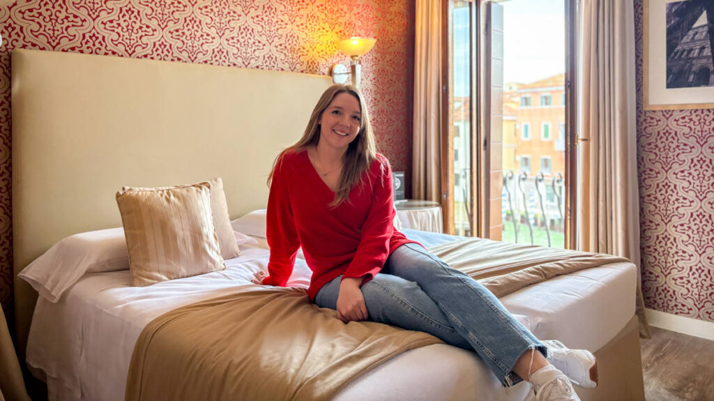 The author, Taylor Herperger sitting on her bed at Hotel Principe