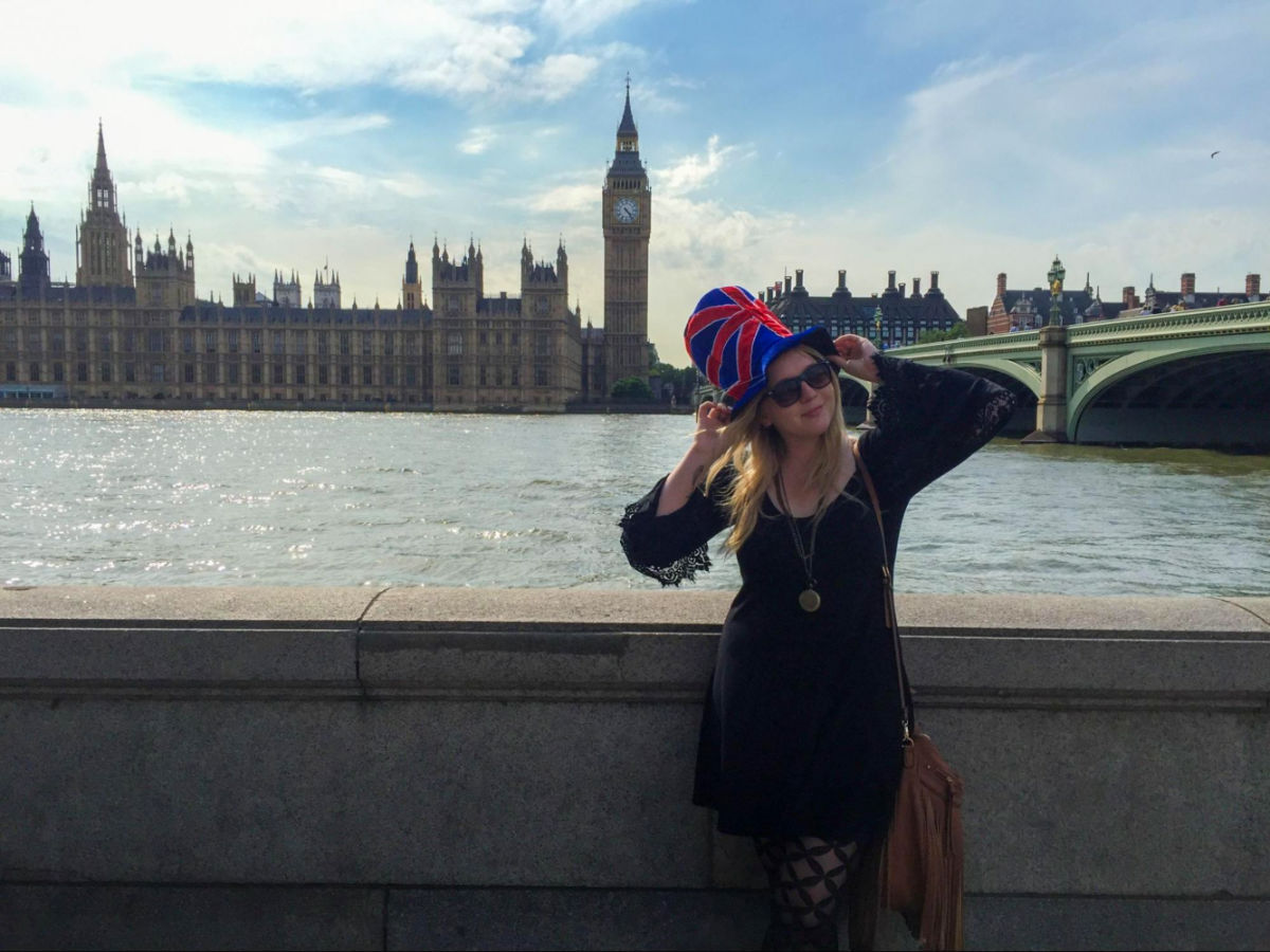 Travel Lemming's Senior Editor Taylor taking a photo with Big Ben in the background while wearing a UK hat