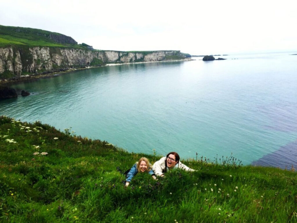 Travel Lemming's Senior Editor Taylor and her friend jokingly trying not to slip off a cliff in Northern Ireland