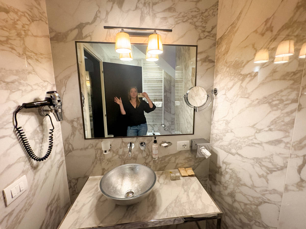 The author Taylor Herperger, smiling for a photo in front of the bathroom mirror