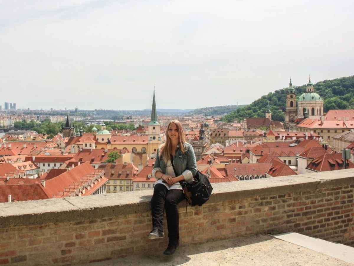 Travel Lemming's Senior Editor Taylor taking a photo with a view of Prague