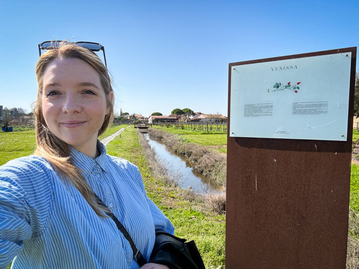 The author Taylor Herperger, smiling for a photo near the signage in Venissa Wine Resort