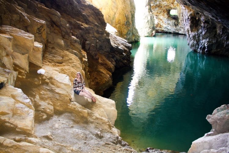 Taylor sits on the rock near a turquoise body of water in Wallingford-back Mine in Quebec