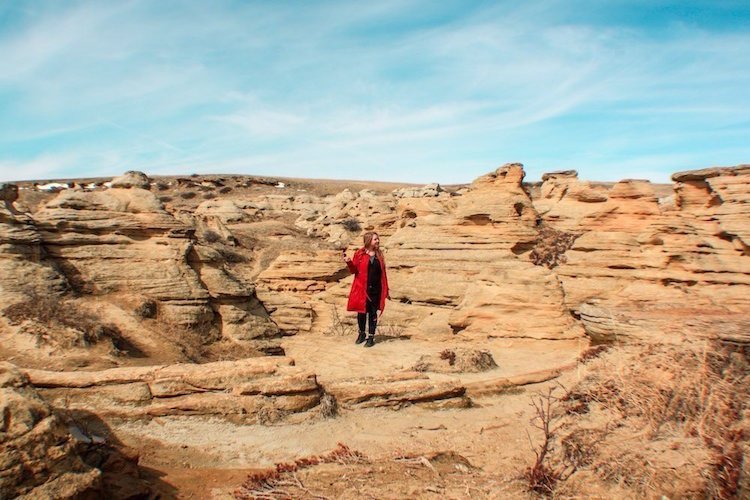 Taylor stands among red rock hoodoos in Writing-On-Stone Provincial Park