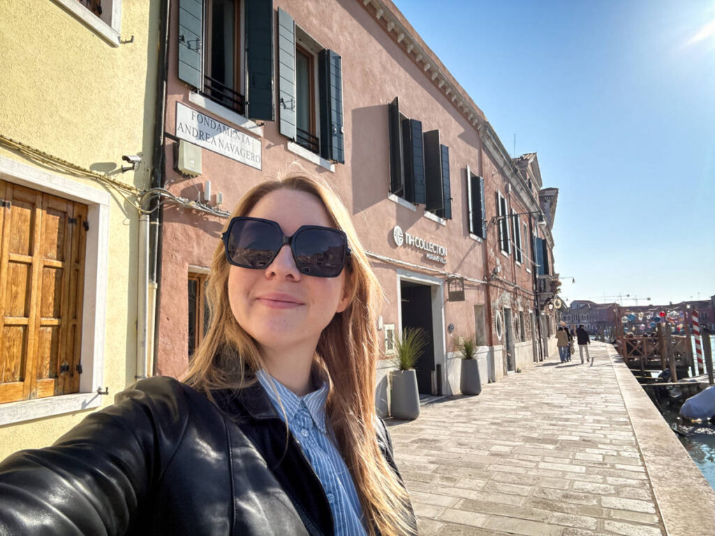 The author Taylor Herperger, smiling for a photo in front of the NH Collection Venezia Murano Villa