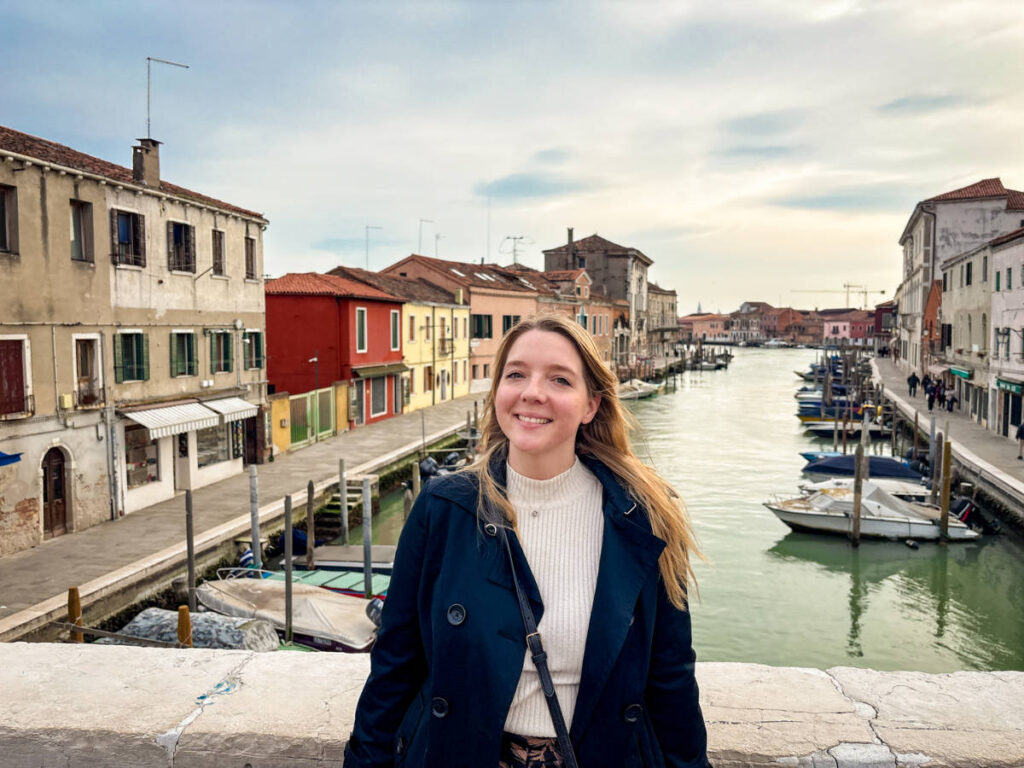The author Taylor Herperger, smiling for a photo on a bridge in Murano