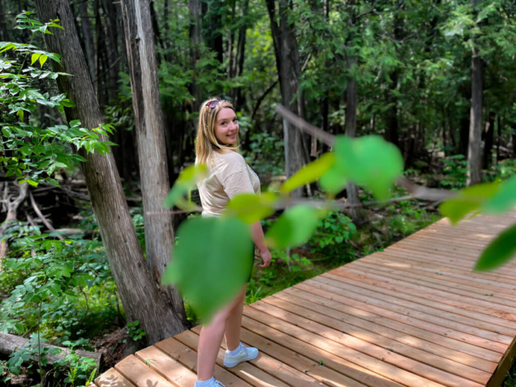 The author Taylor Herpeger, posing for a photo on the boardwalk behind the  leaves