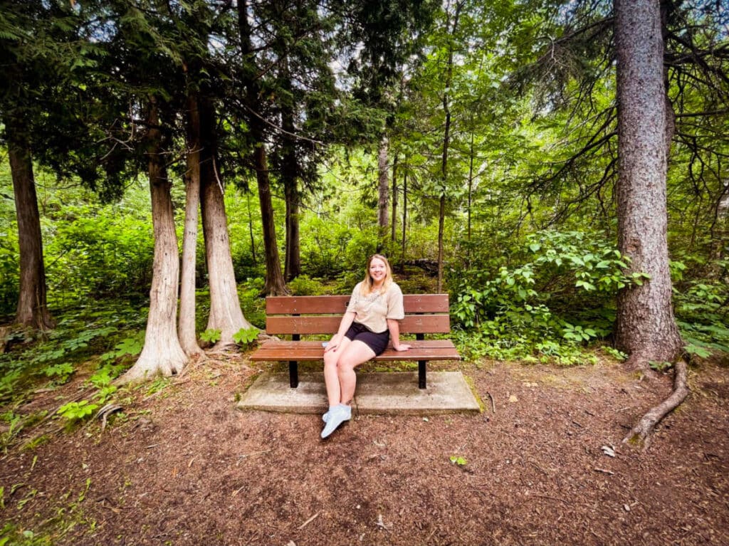 The author Taylor Herperger, sitting on a bench at Cedar Bog Trail in Birds Hill Provincial Park