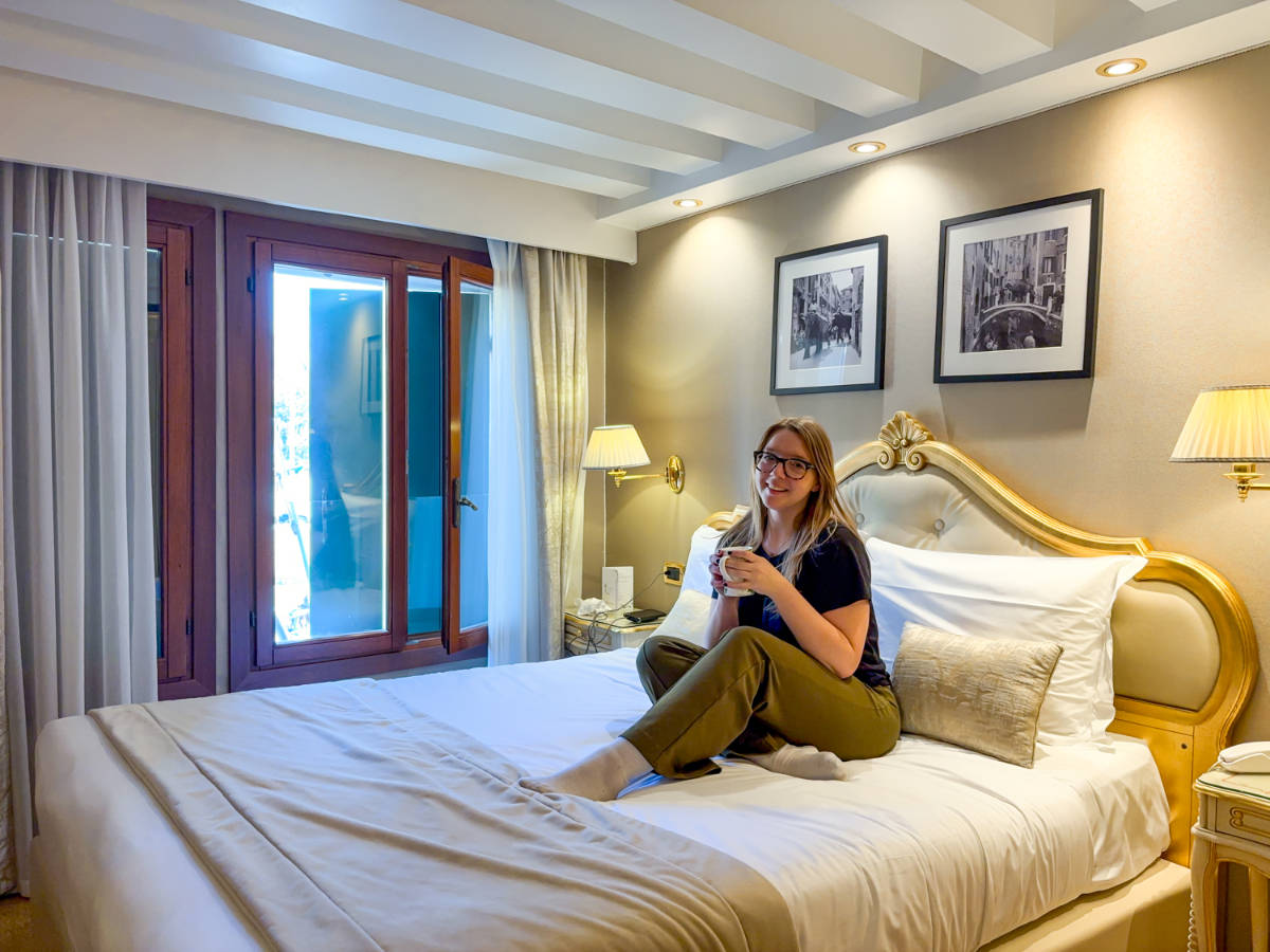 The author Taylor Herperger, sitting on the bed at Hotel Olimpia
