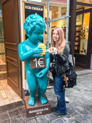 Travel Lemming's Senior Editor Taylor posing for a photo next to a blue Manneken-Pis in Brussels