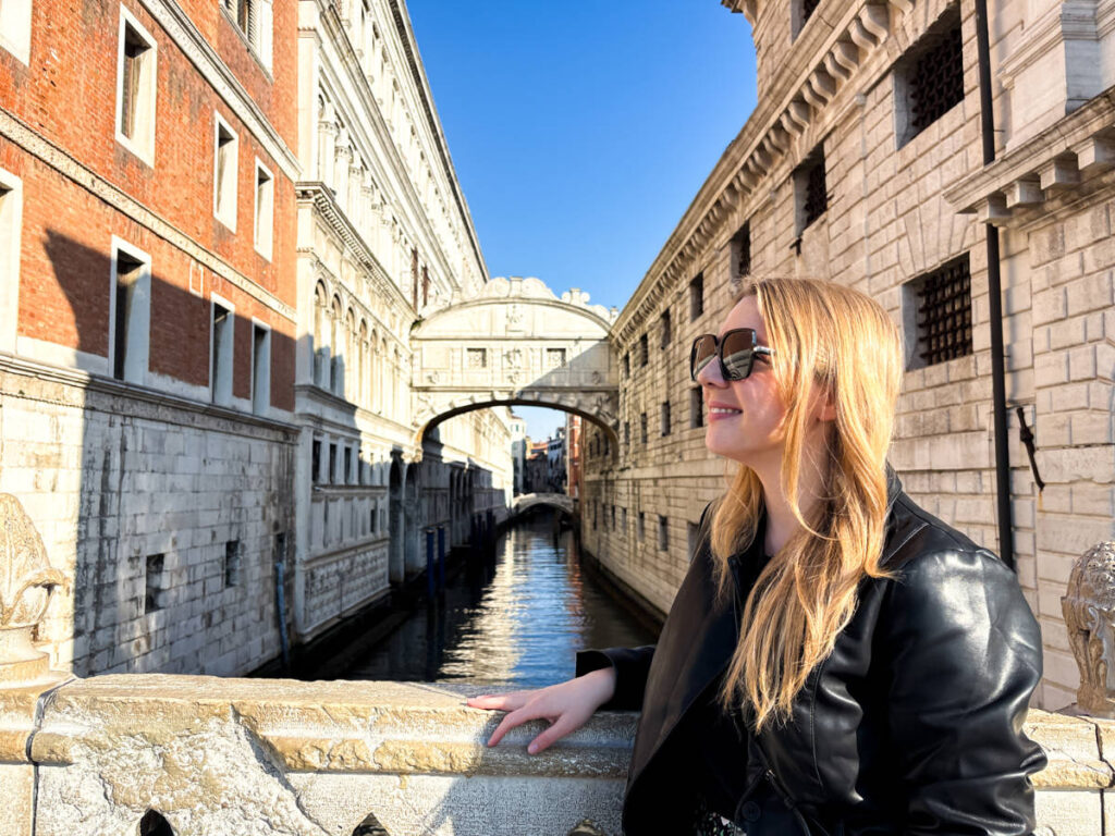 The author Taylor Herperger, smiling for a photo in front of the Bridge of Sighs