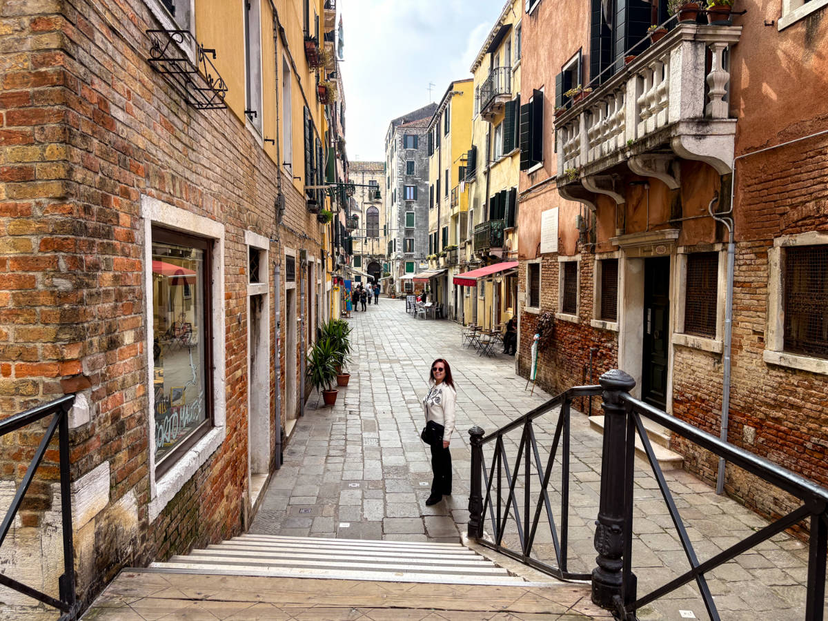 The author's mother standing at the bottom of the stairs in Cannaregio