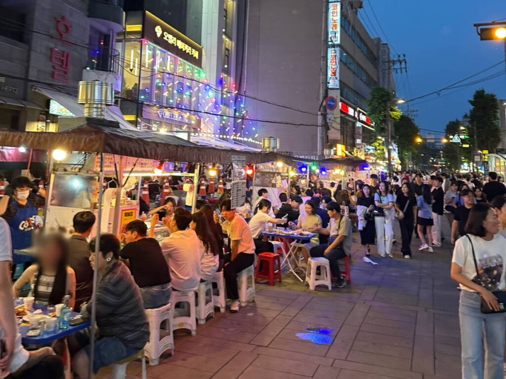 people enjoying and drinking at the tent bars set up along Jogno Pocha Street