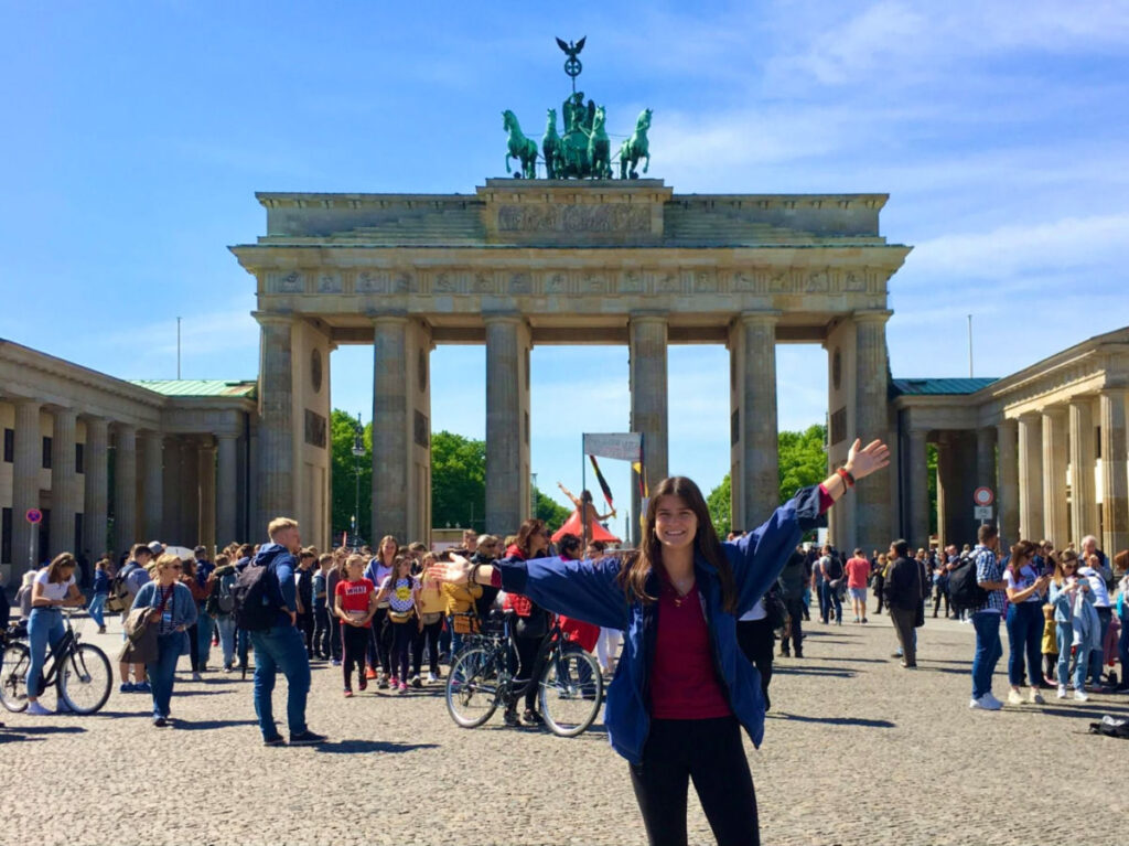 Travel Lemming writer Betty in front of the Brandenburg Gate, with a naked protestor in the background