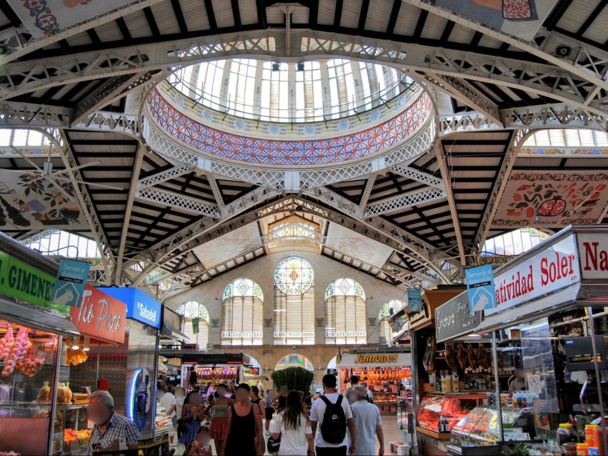 View of people shopping and the ironwork and stained glass of Valencia’s Central Market