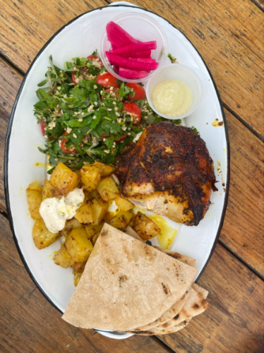 A plate of a chicken meal on a wooden table at Ojai Rotie
