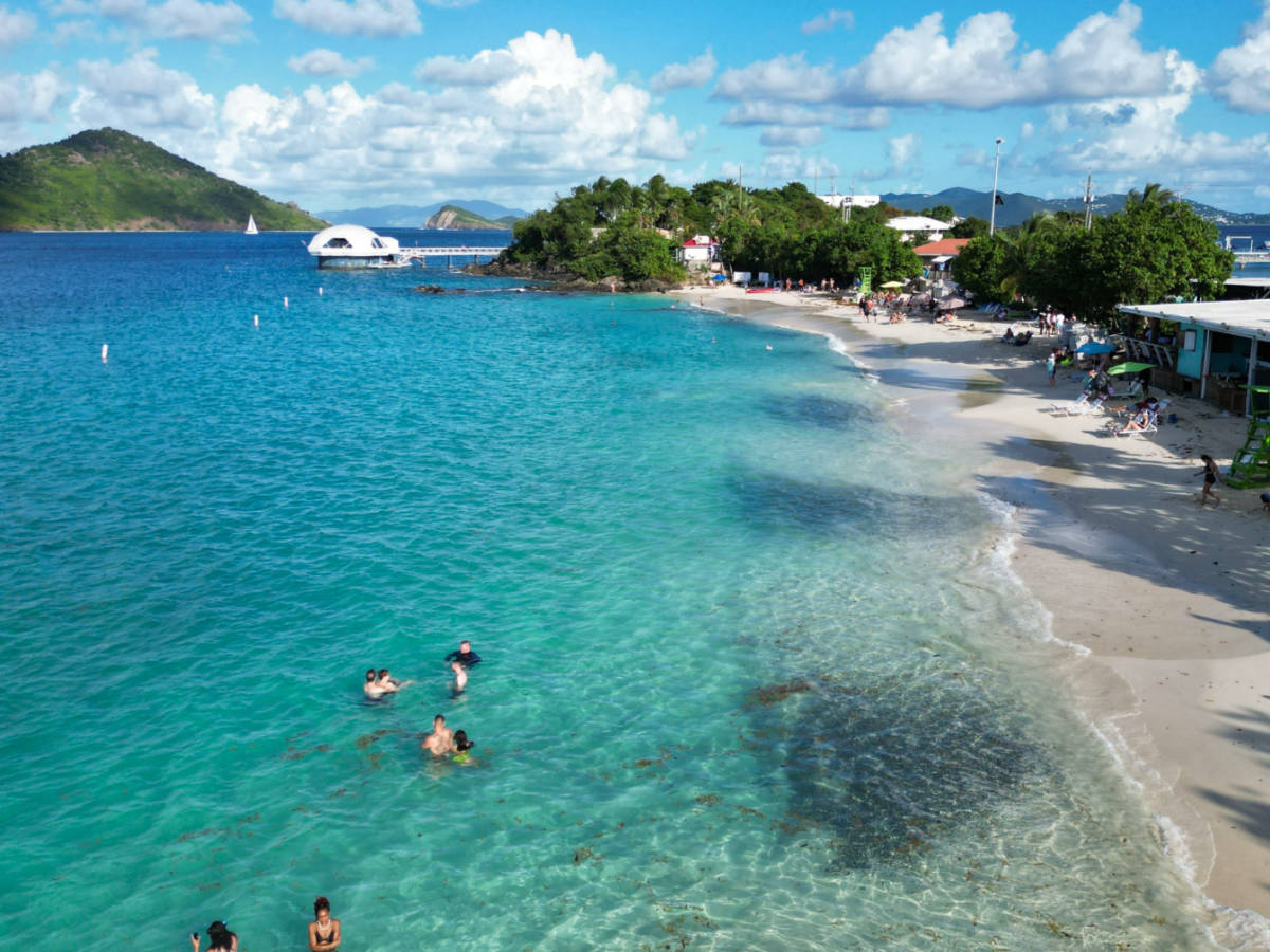 A drone shot of people swimming in the water at Coki Point beach