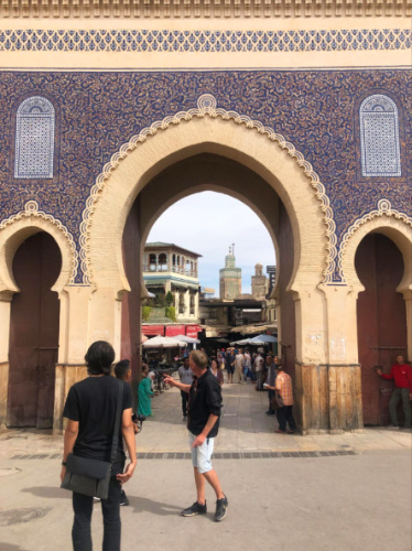 People walking through a archway showcasing the Fes Medina architecture