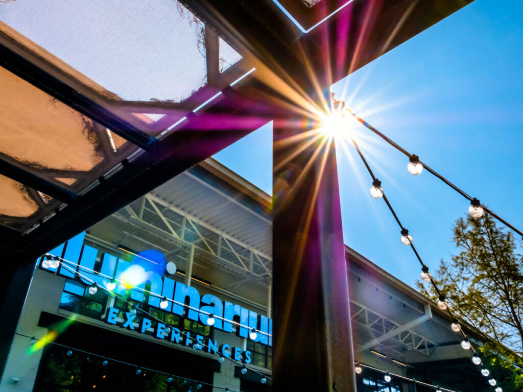 Sunlight bursts through the beams of a patio structure outside Illuminarium
