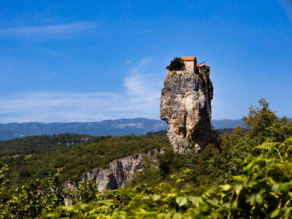 View of the orthodox church and the abbot cell on the rocky cliff of Katskhi Pillar surrounded by greenery