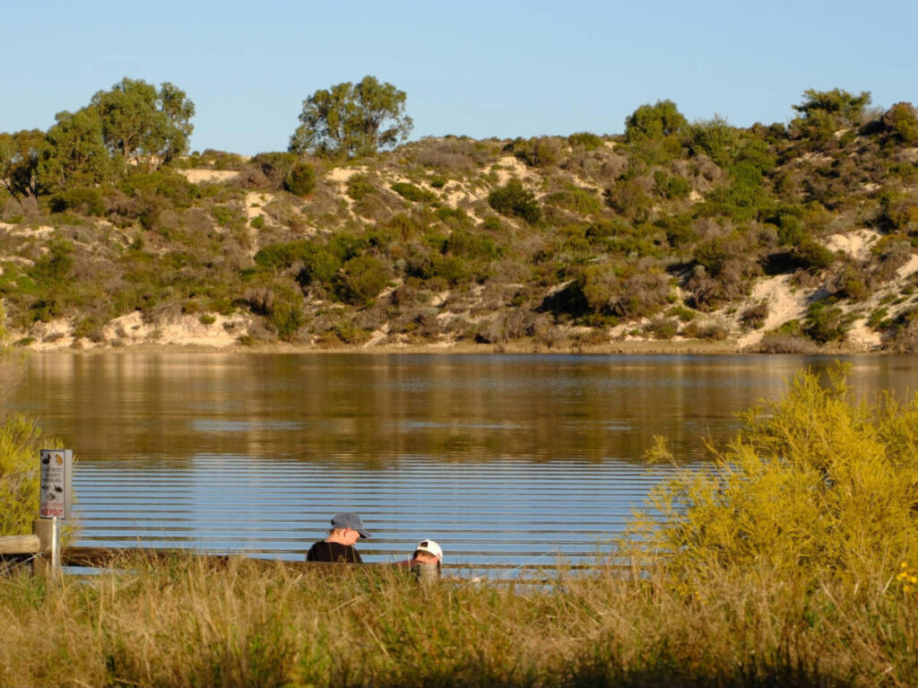 People chilling near the Moore River surrounded by greenery in Guilderton