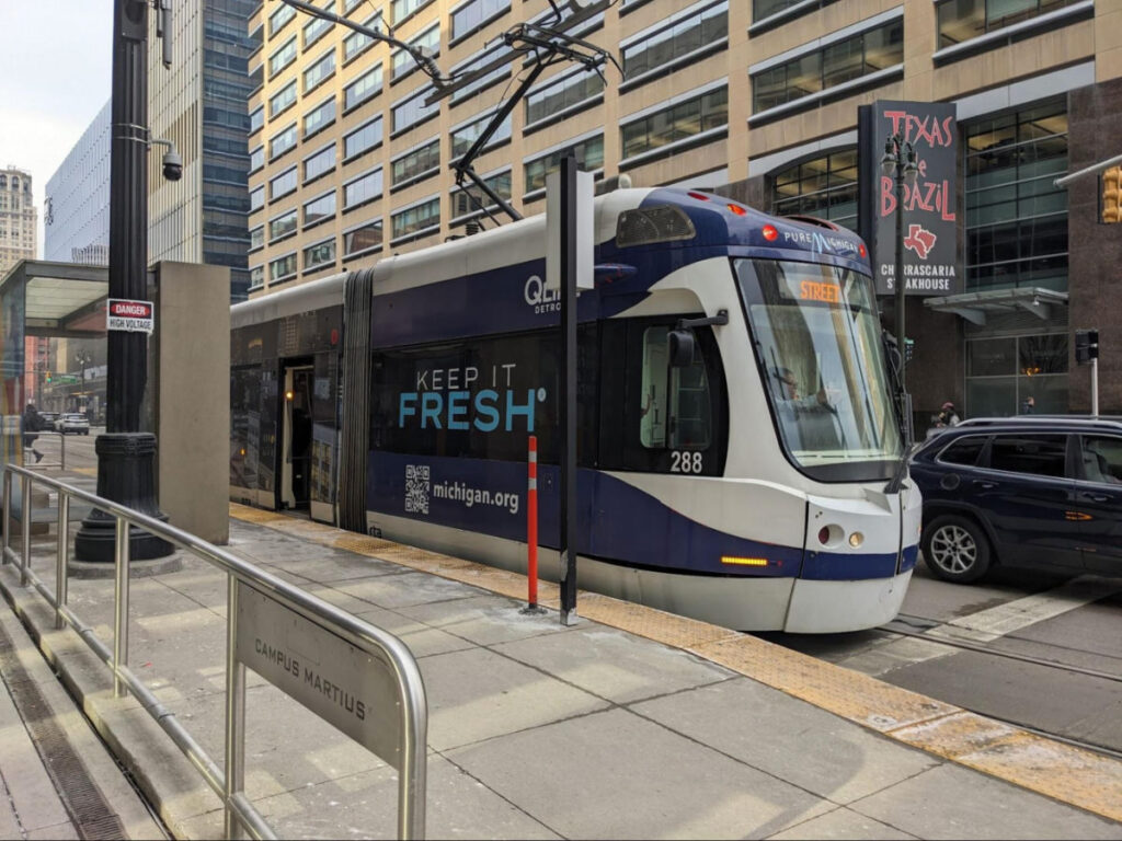 The QLINE train on the tracks at a city station.