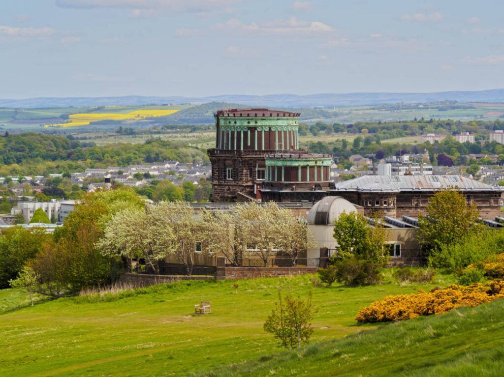 The Royal Observatory Edinburgh surrounded by greenery with an overlooking view