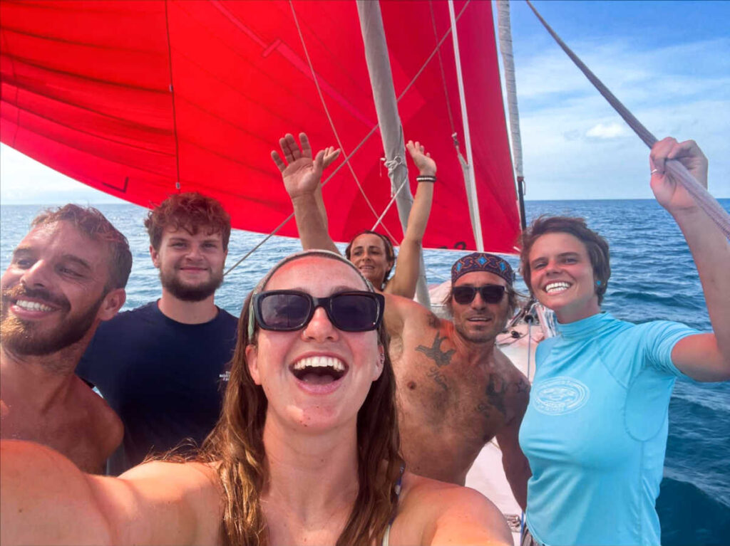 The author Laura McFarland and the other sailing crew smiling for a photo on the boat