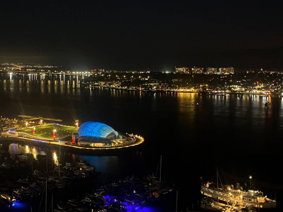 Aerial view of The Shell, lit up in blue, near the San Diego Bay at night