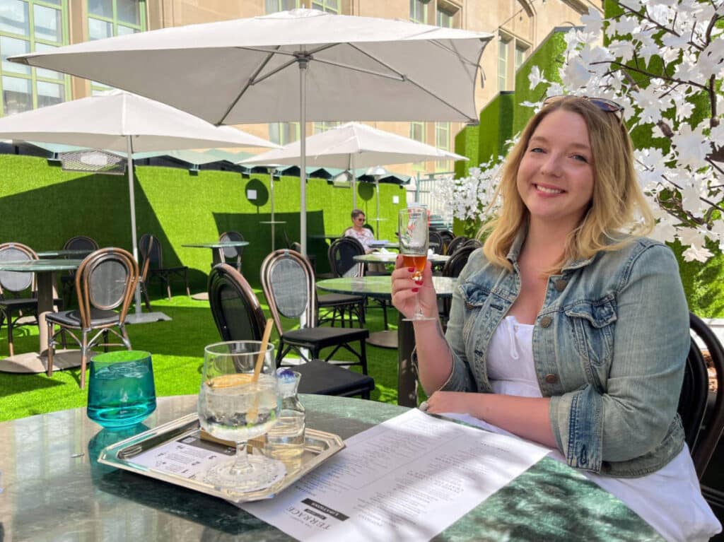 The author, Taylor Herperger holding a glass of orange wine at The Sunset Terrace Eat + Drink