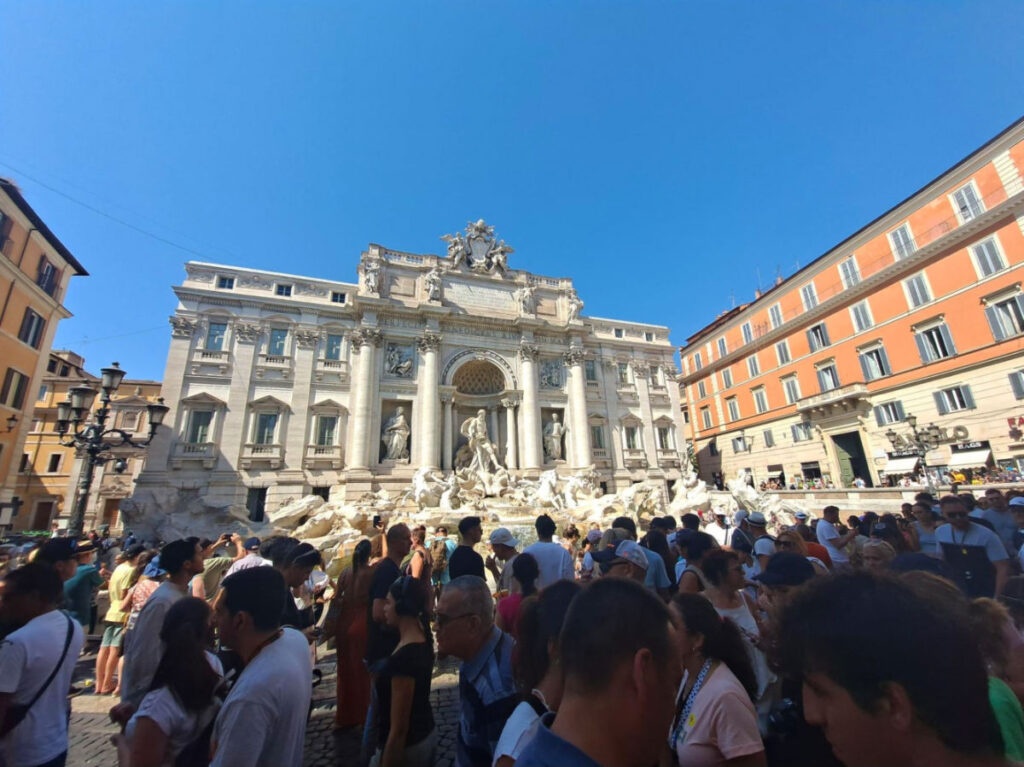 Tourists taking pictures and walking near The Trevi Fountain