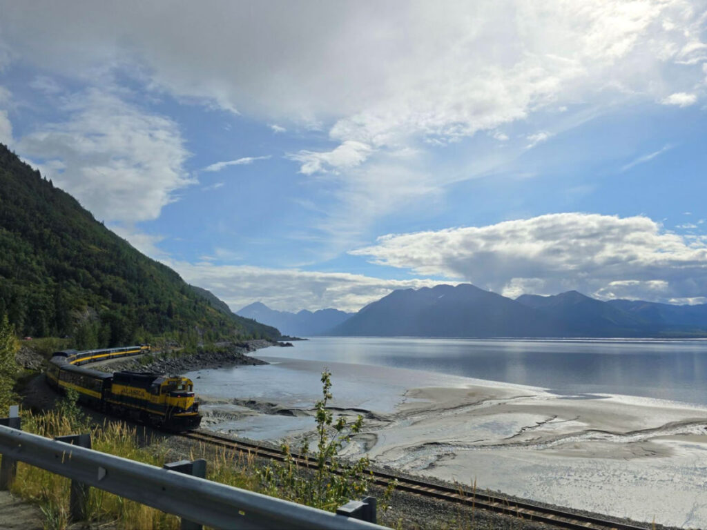 A yellow train travelling beside the Turnagain Arm