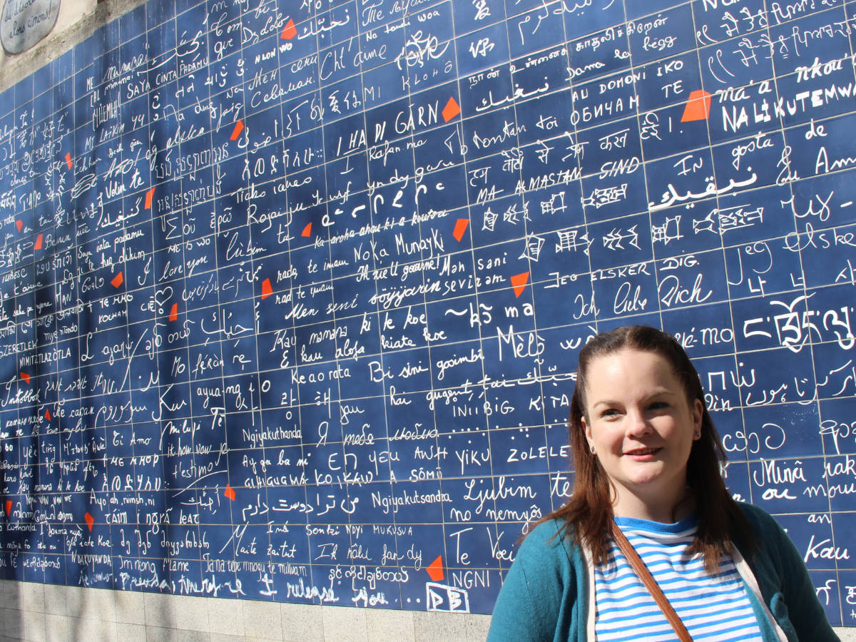 The author, Rachel Kapelke Dale posing for a photo in front of the “Mur des je t’aime”