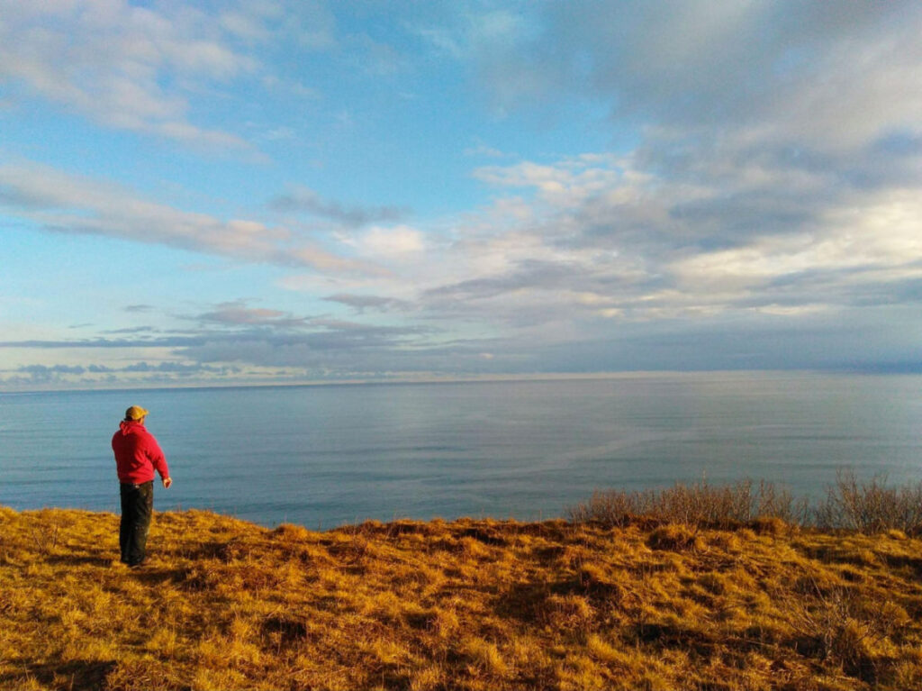A man in red jacket gazing at the sea at Pasagshak