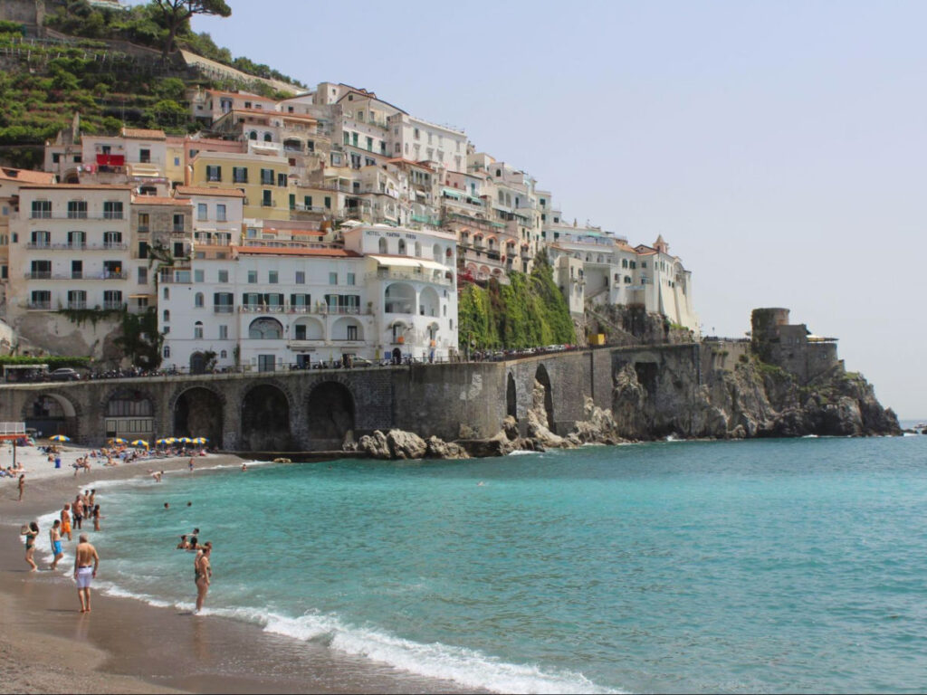 Beachgoers strolling on sandy shores in Amalfi, Italy