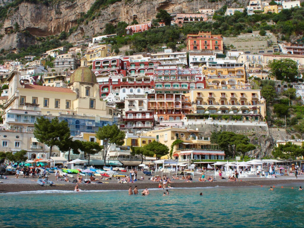 Beachgoers strolling on sandy shores in the town of Positano
