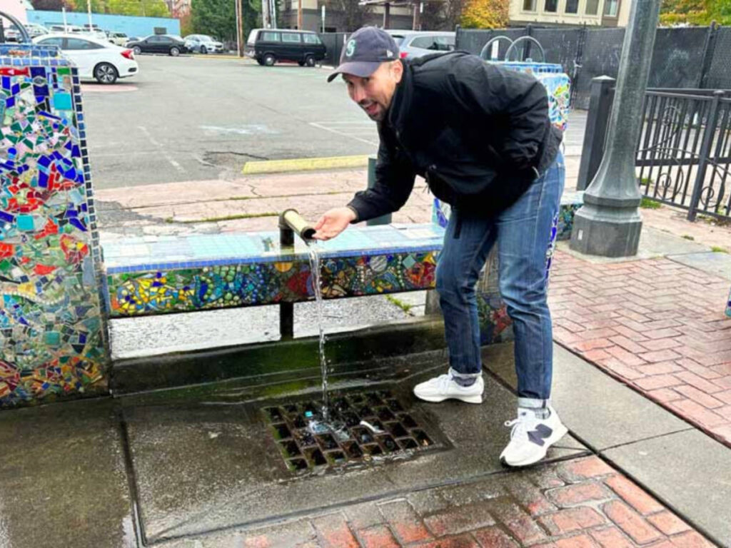 Author's husband sampling the well water in Olympia