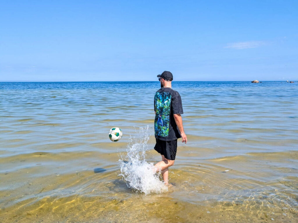 The author Thom Brown, playing with a ball at the Estonian sea on a sunny day