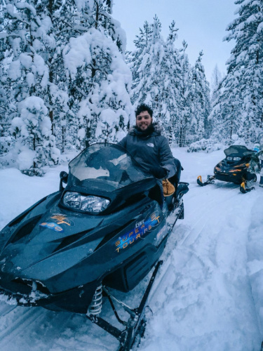 The author Thom Brown, riding a snowmobile in the woods near Tartu