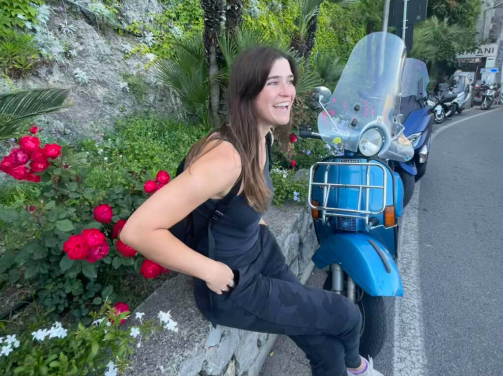 Author Betty sitting on a roadside in Italy with her rented Vespa