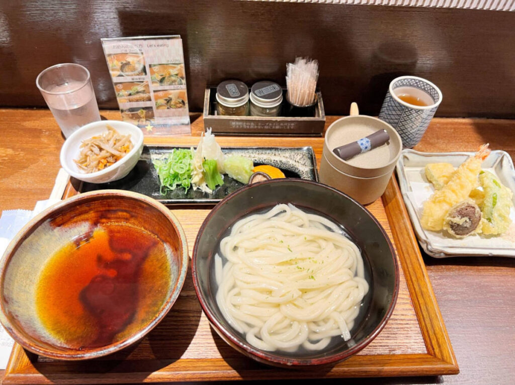 A bowl of udon, with tempura, sushi and other side dishes from Shijo Pontocho
