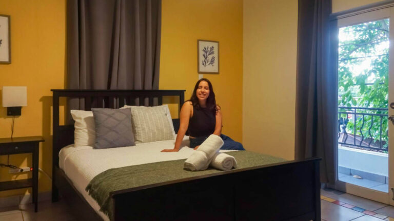 The author Vanessa Ramos, sitting on the bed in Rincón Plaza Hotel