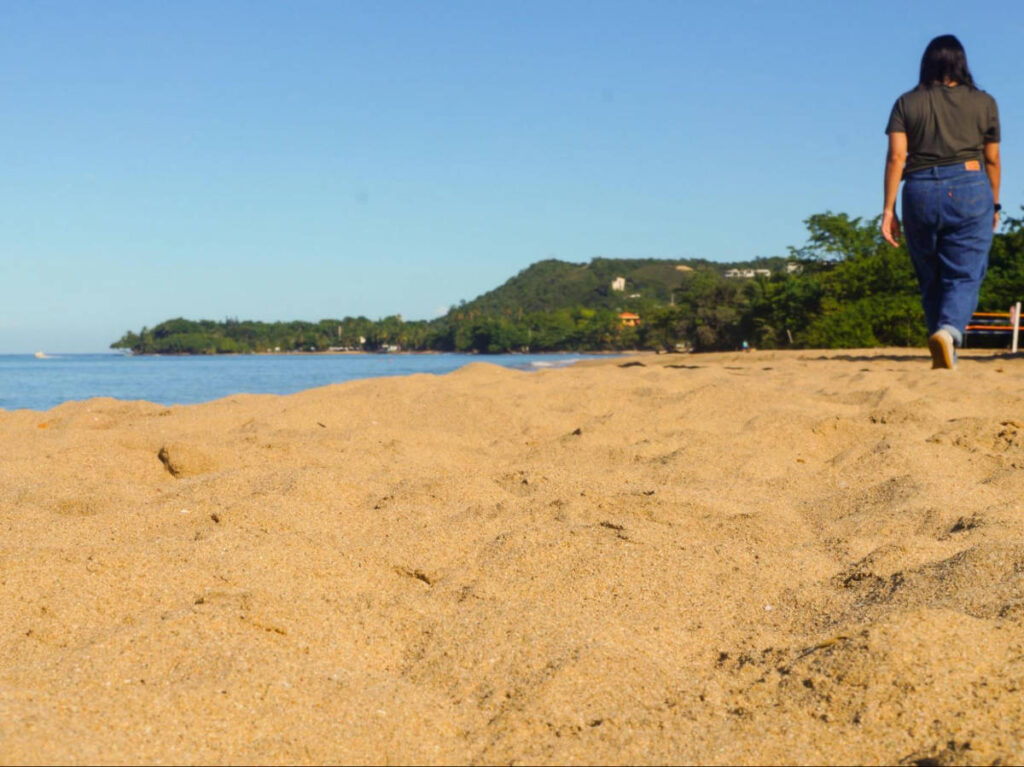 The author Vanessa Ramos walking along the sandy beach at Doña Lala Beach