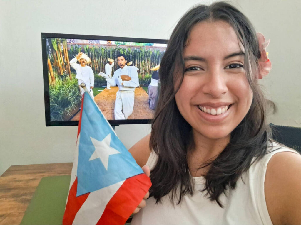 The author Vanessa Ramos, holding a Puerto Rico flag while watching the 2026 Super Bowl Half Time Show