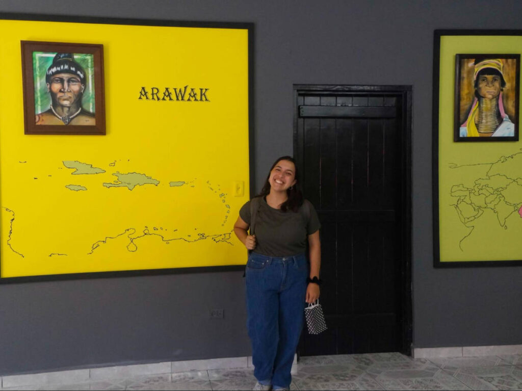 The author Vanessa Ramos, posing for a photo in front of the portraits at Casa de la Cultura
