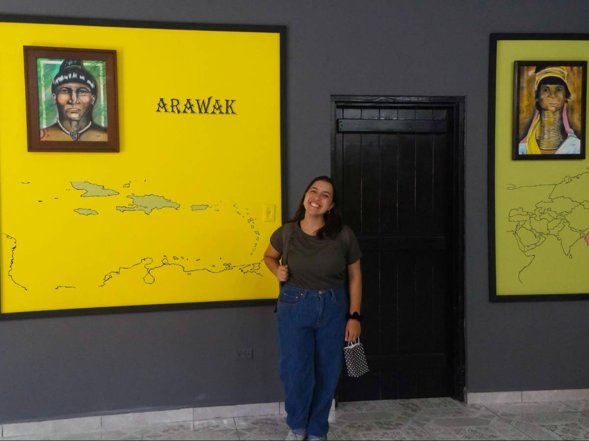 The author Vanessa Ramos, posing for a photo in front of the portraits at Casa de la Cultura